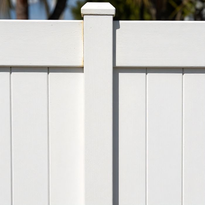 Chalking and fading on the sunlit face of a white vinyl fence panel.
